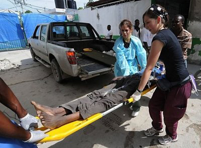 Enfermeiras ajudam uma vítima da cólera a entrar num hospital em Port-au-Prince