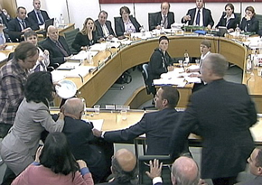 Durante as audições na Câmara dos Comuns, Murdoch é atacado com uma tarte de creme de barbear por um comediante indignado com o escândalo