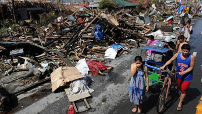 Residentes passam por casas destruídas e cadáveres espalhados numa rua de Tacloban, ilha de Leyte, Filipinas, após a passagem do tufão Yolanda (Haiyan) em Novembro de 2013